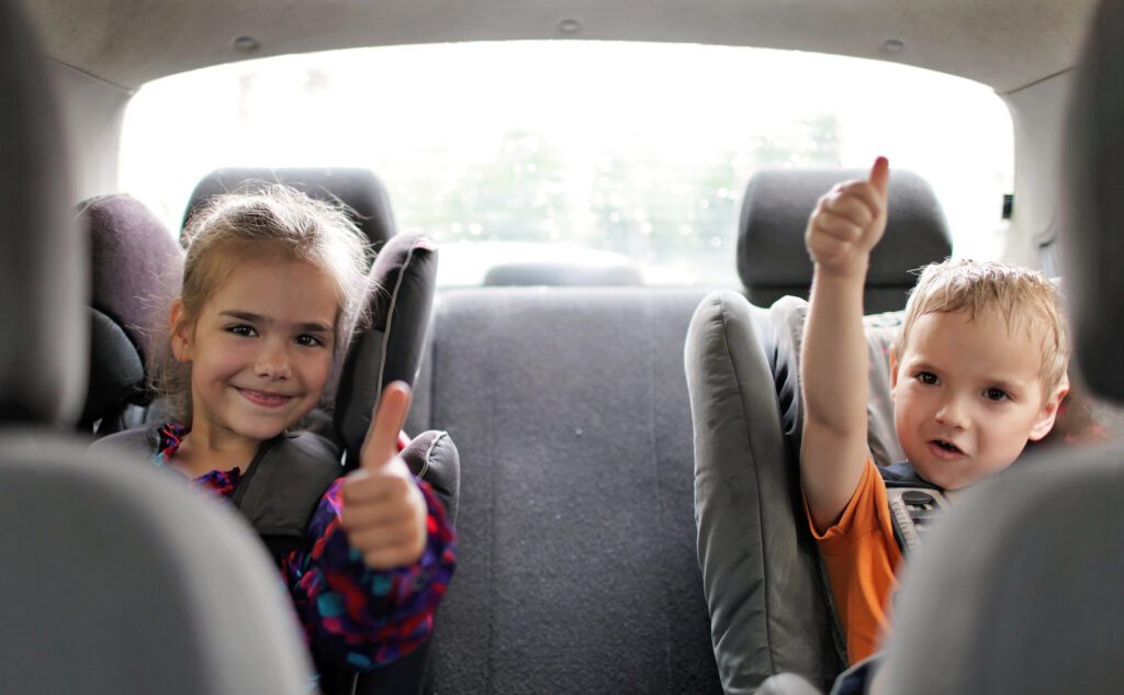2 young children in car seats enjoying talking to their parents
